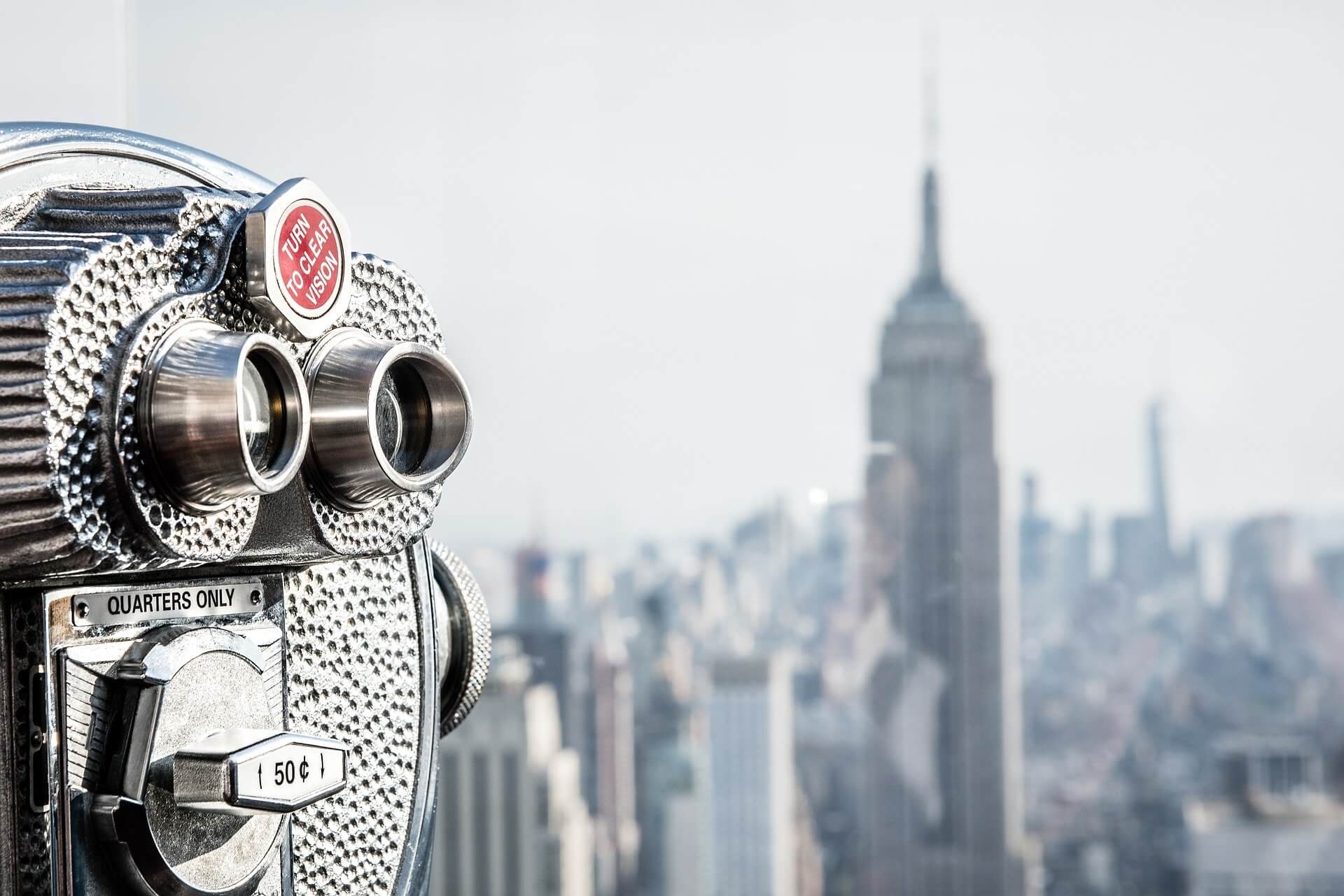 Nahaufnahme eines touristischen Fernrohrs mit New Yorks Dächern und Wolkenkratzern im Hintergrund